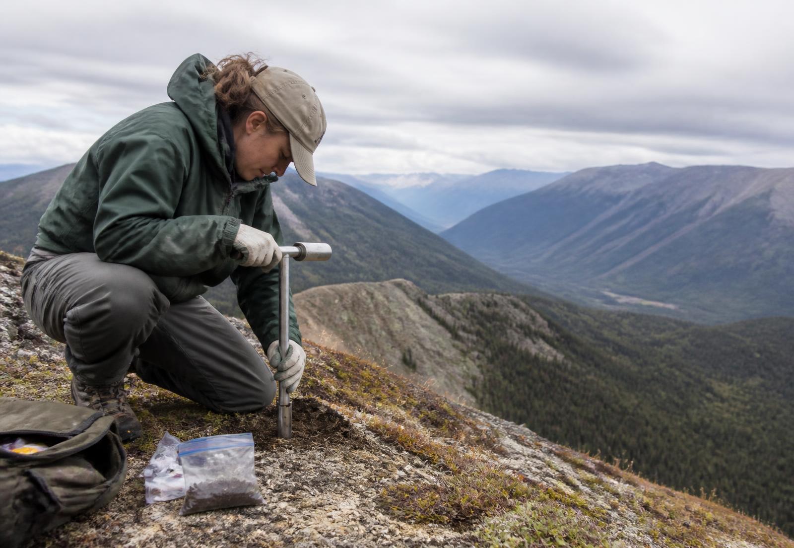 Field geologist collecting a soil sample on an alpine ridge in British Columbia